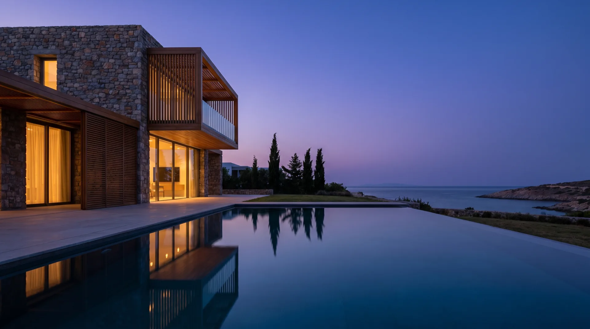 A contemporary Mediterranean luxury villa at blue hour with an infinity pool and the Aegean sea beyond