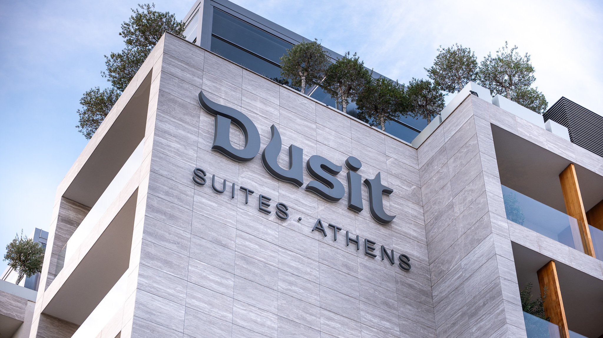 Dusit Suites Athens, hero facade close-up of signage on travertine cladding