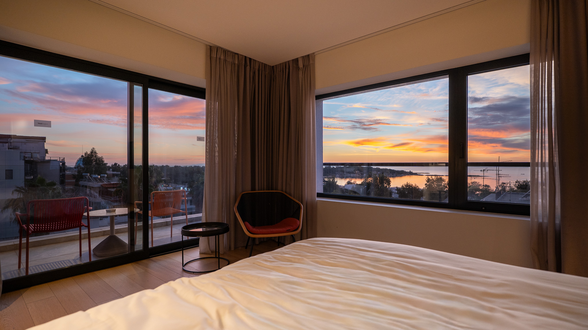 Dusit Suites Athens, suite bedroom at sunset with corner sea-view glazing