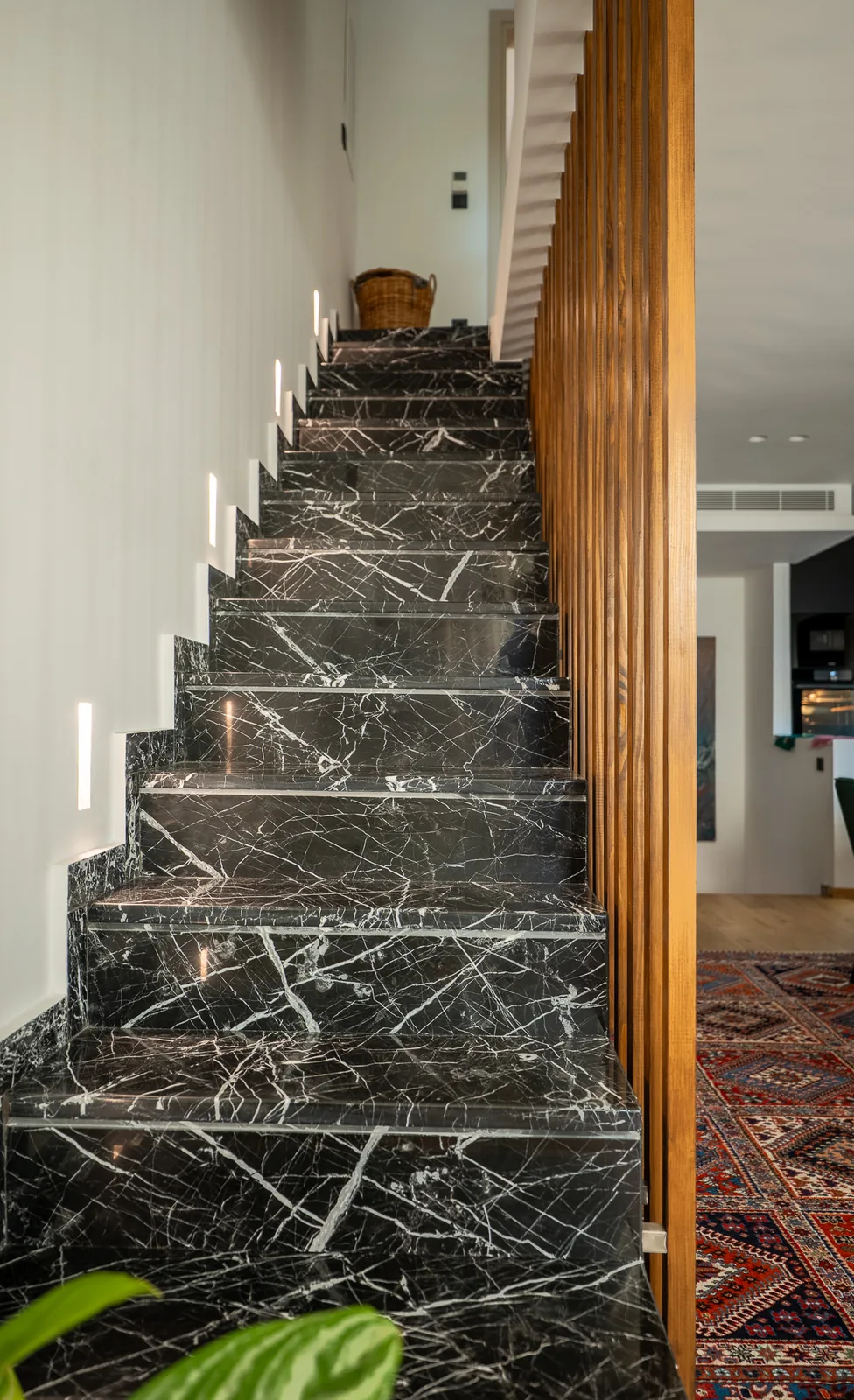 Kitsos Constructions residence, the dark marble staircase behind a timber screen
