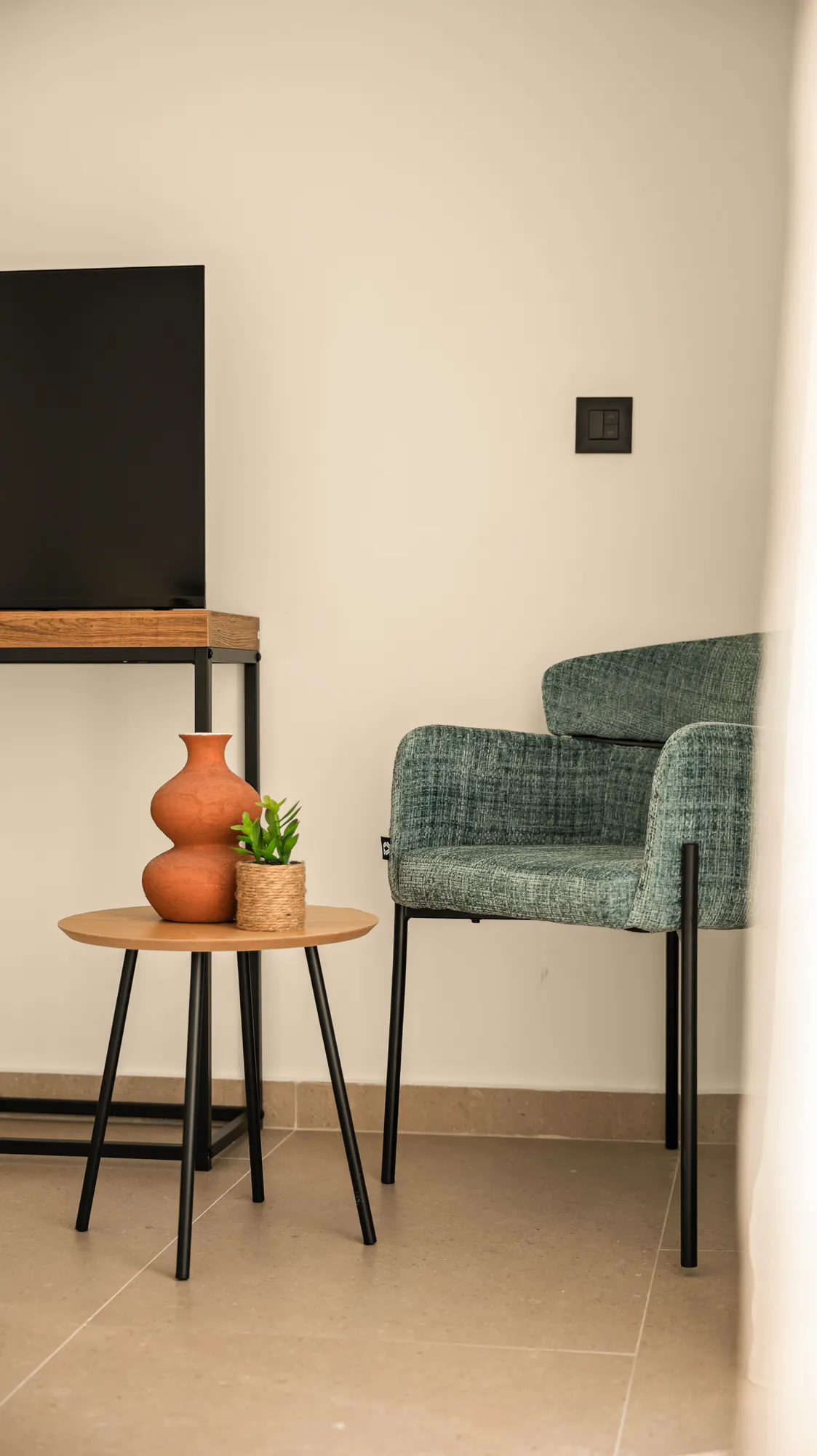 ORMOS Piraeus, a green armchair and a side table by the window