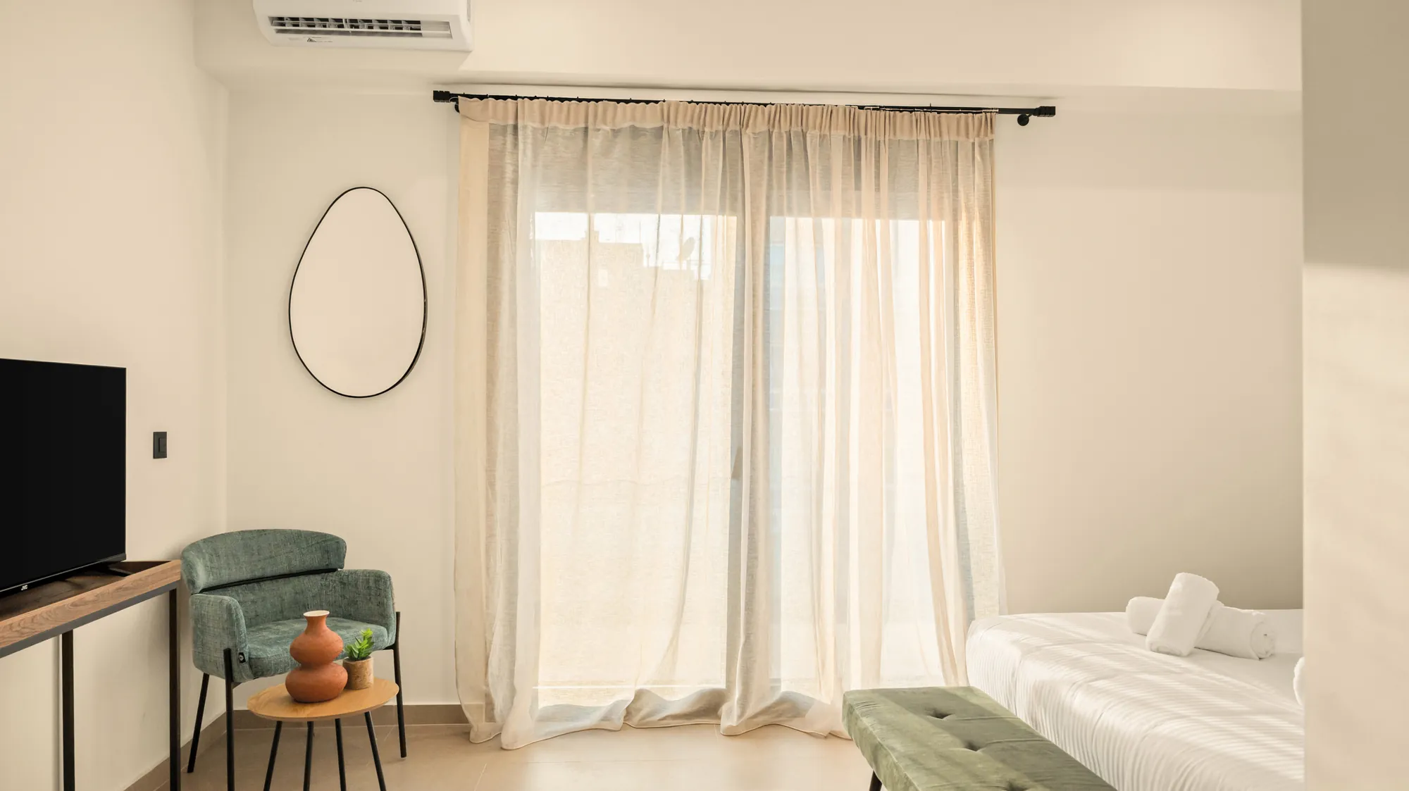 ORMOS Piraeus, the balcony doors behind linen curtains, the armchair and the mirror