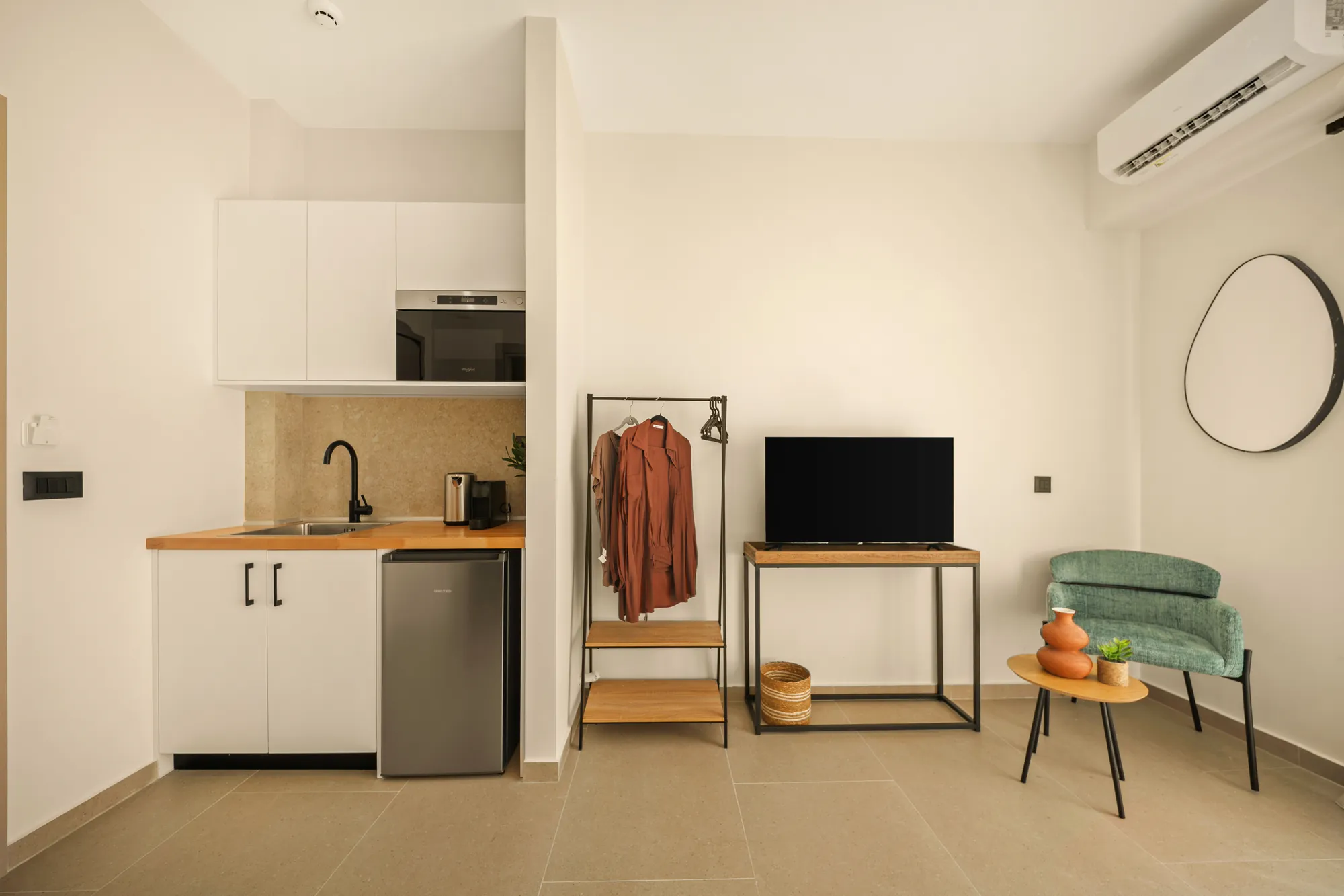 ORMOS Piraeus, the kitchenette, the clothes rail and the green armchair