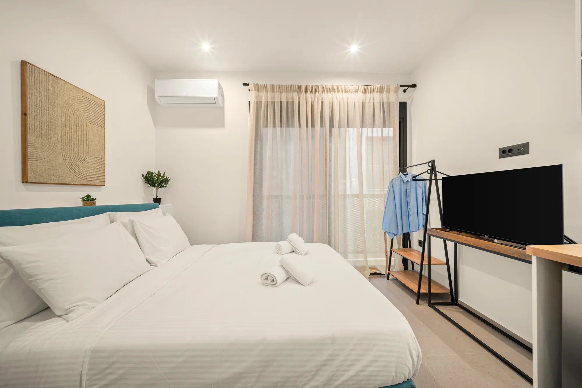 ORMOS Piraeus, a room with the teal bed and the television console