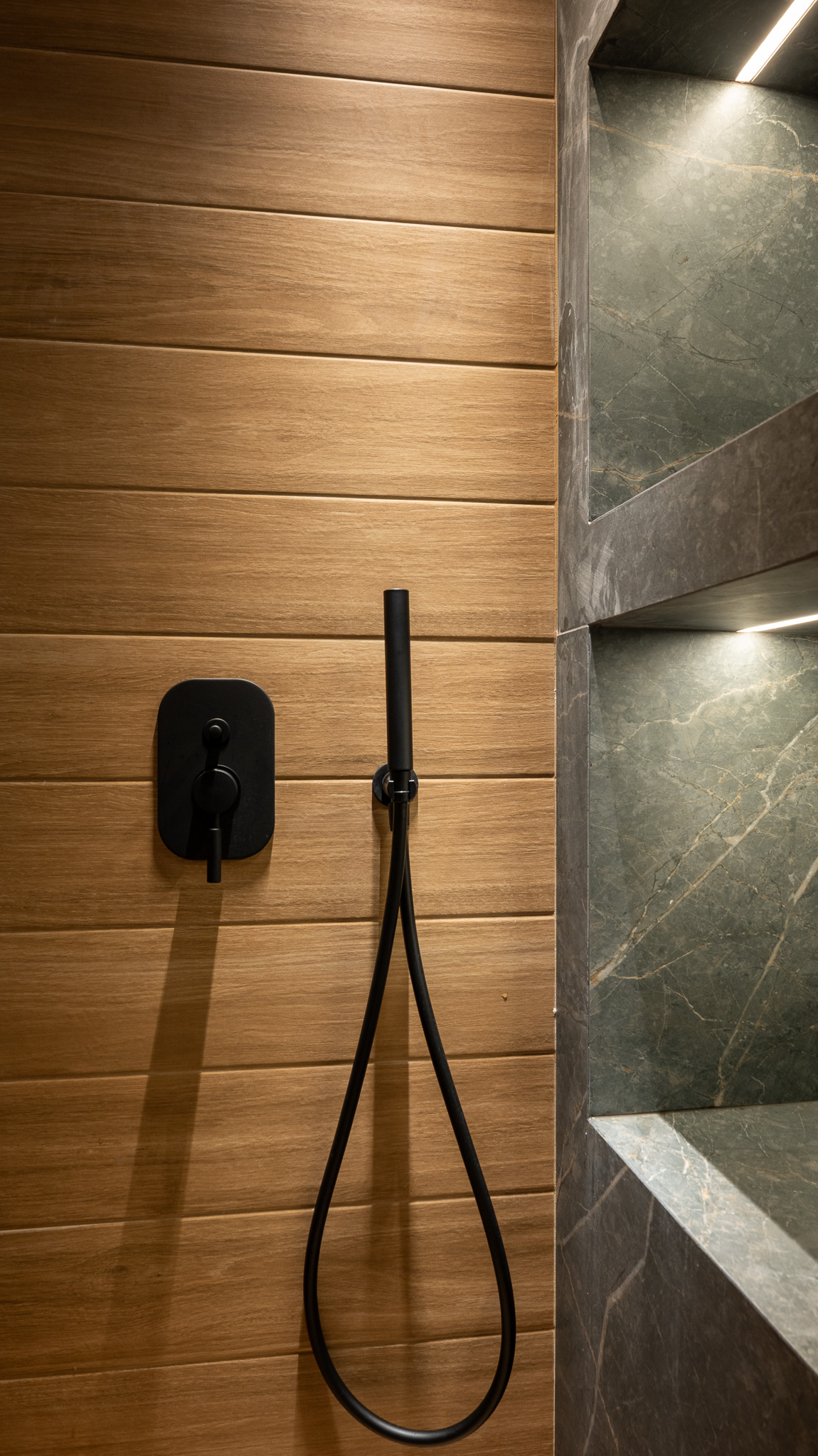 A&K Chorothetisis, shower detail with matte-black mixer and hand-shower on oak plank wall