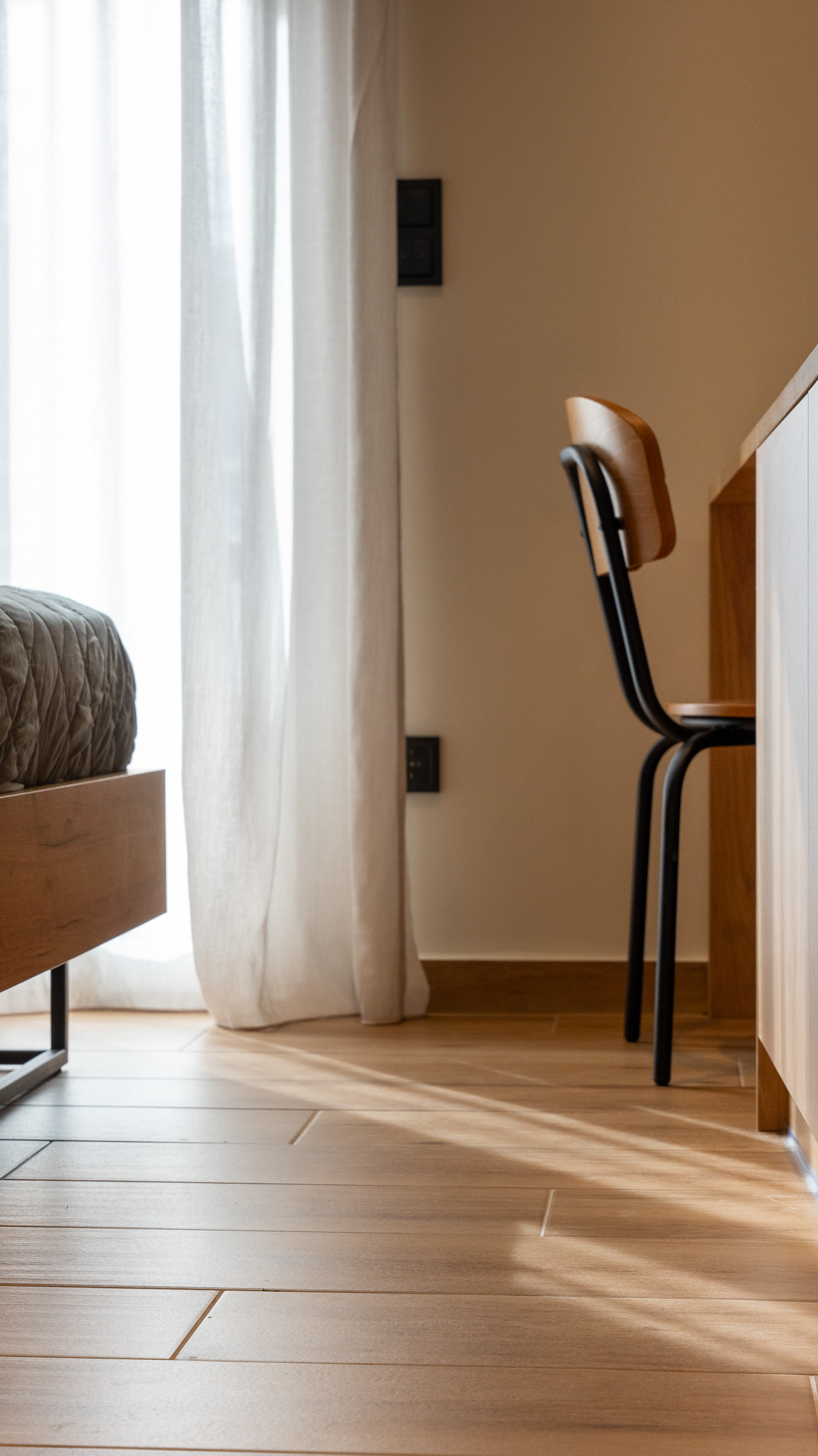 A&K Chorothetisis, bedroom corner with sheer curtain backlight, oak chair and floor planks