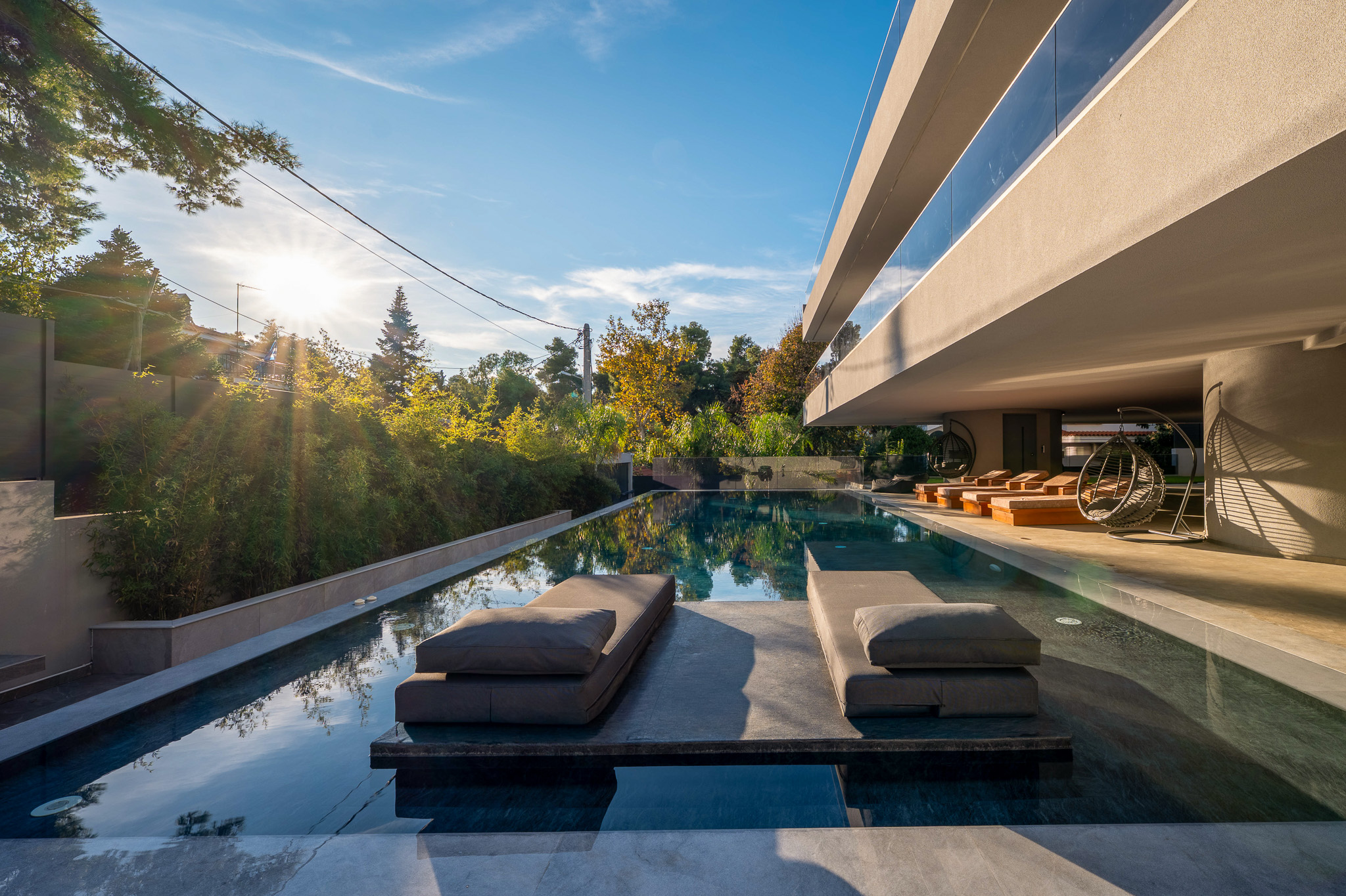 Villa Bond, golden-hour pool platform with sun flare through pines