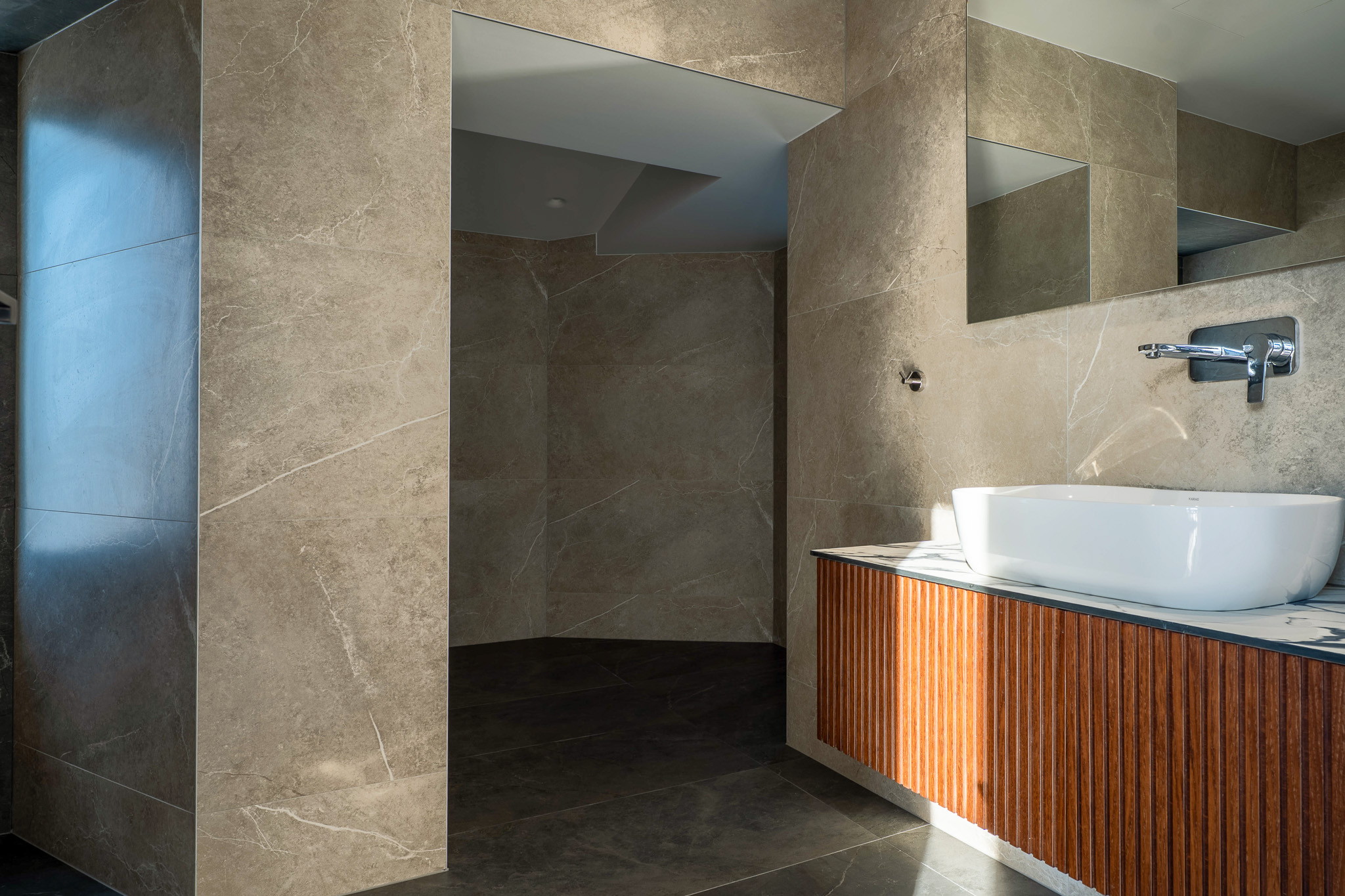 Villa Bond, beige marble bath with wood-slat vanity