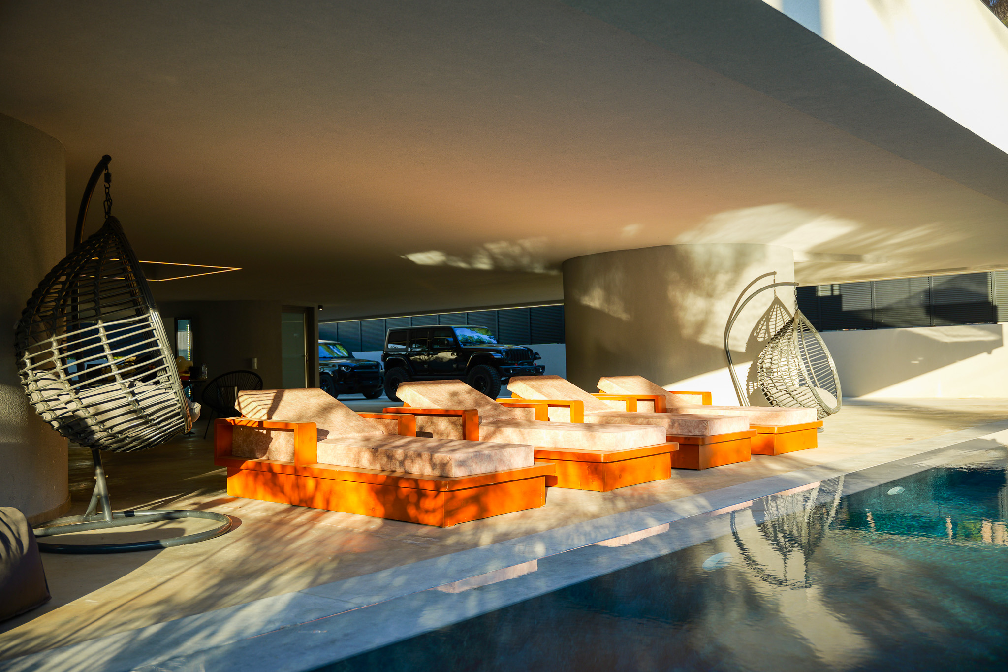 Villa Bond, golden-hour orange loungers with black Jeep beyond