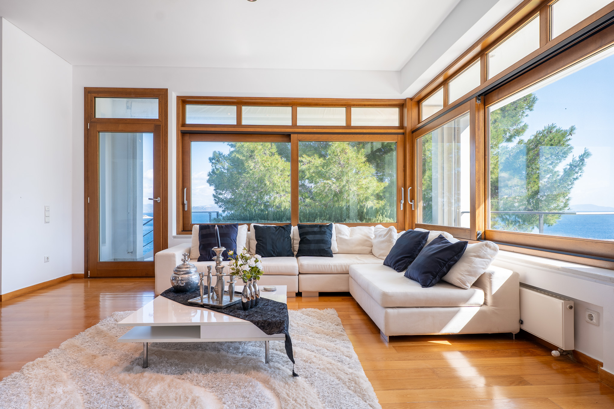 Villa Selene, white sectional sofa under wood-trimmed window wall